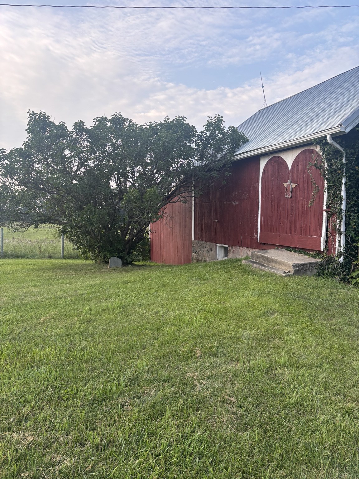 Red barn beside trees and a green lawn