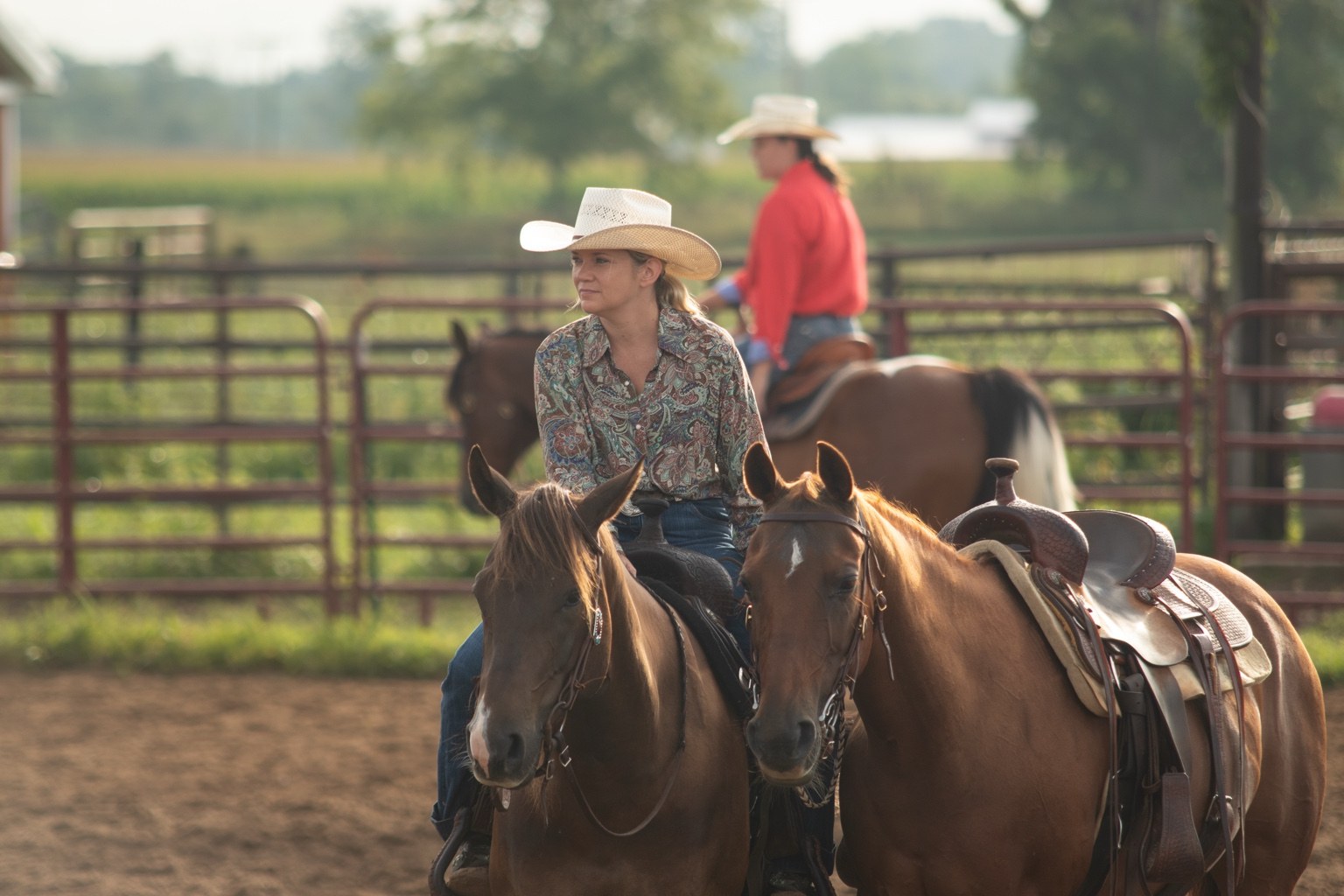 Rider on a bay horse alongside a saddled chestnut horse