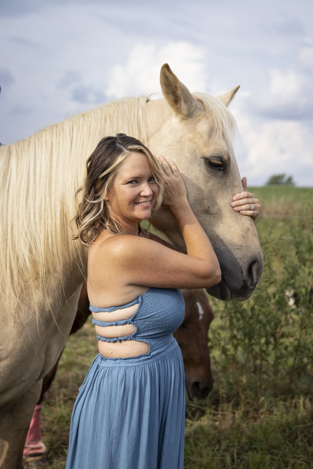 Woman embracing a light-colored horse